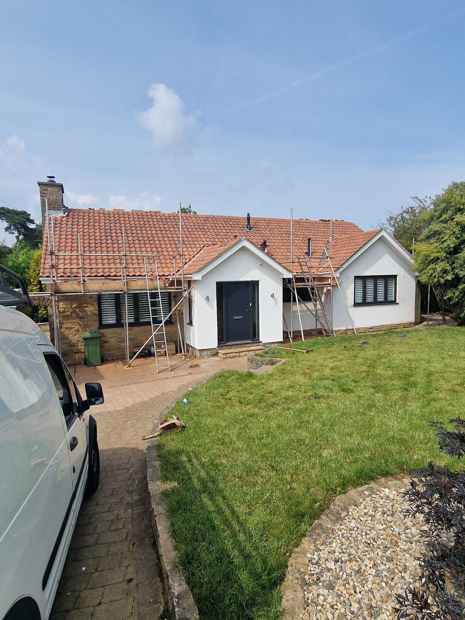 Bungalow with a red tiled roof, scaffolding still up at the side