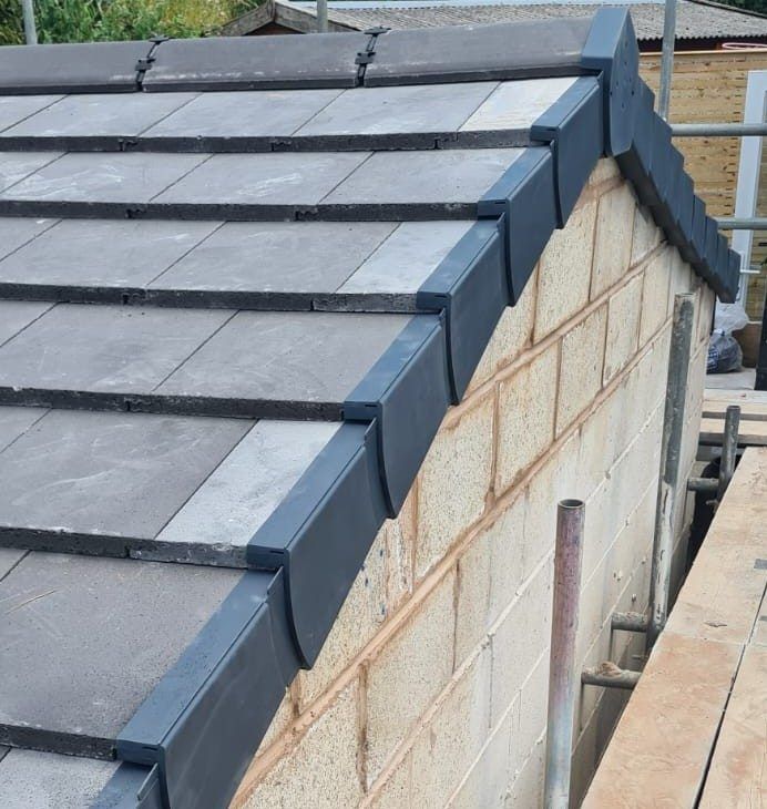 Grey tiled gable with a new dry verge over blockwork