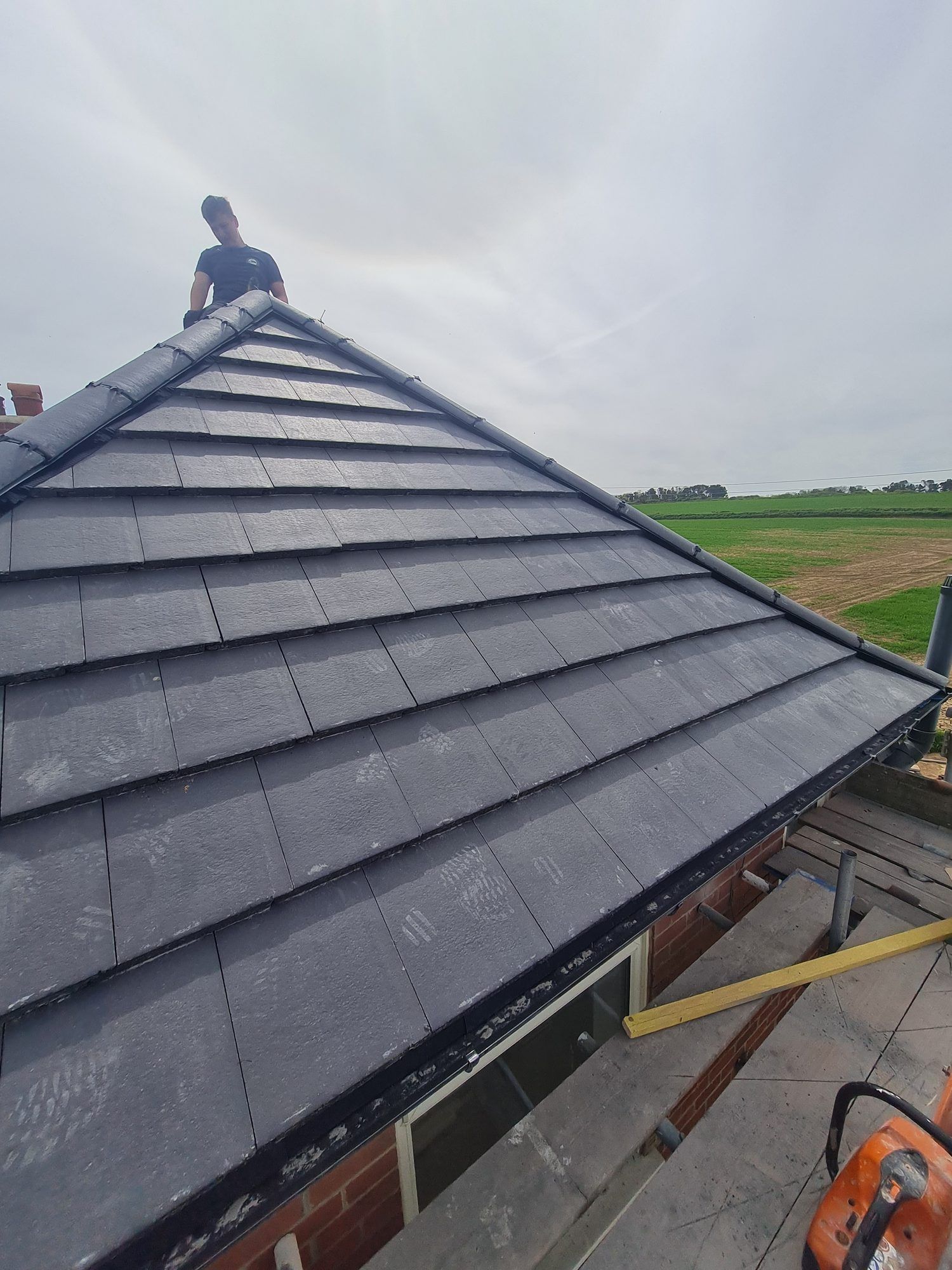 New grey tiled hip roof with fields beyond