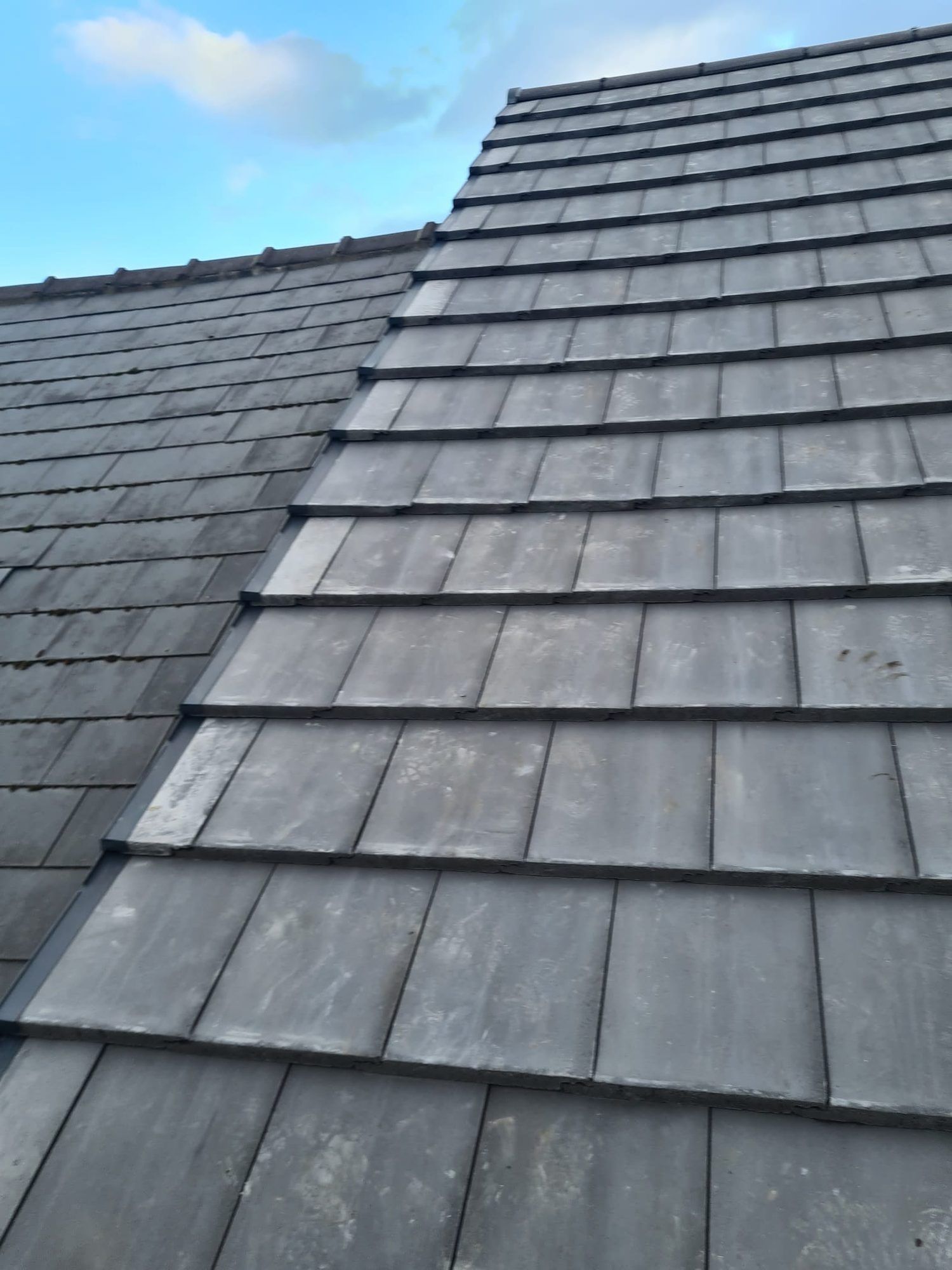 New grey interlocking tiles meeting an older roof