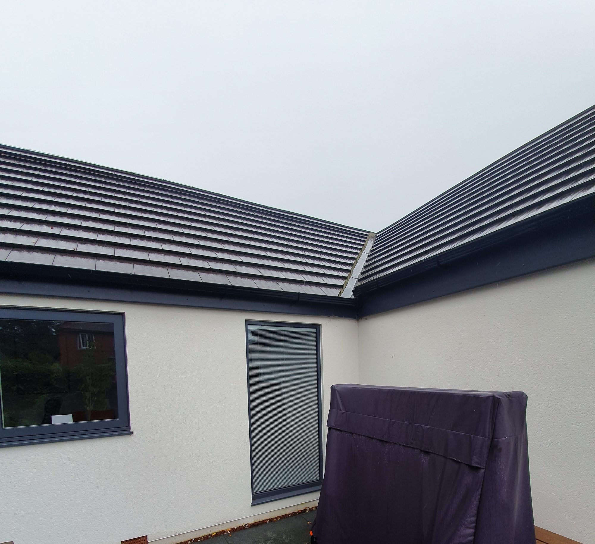 New grey tiled roof on a rendered bungalow extension