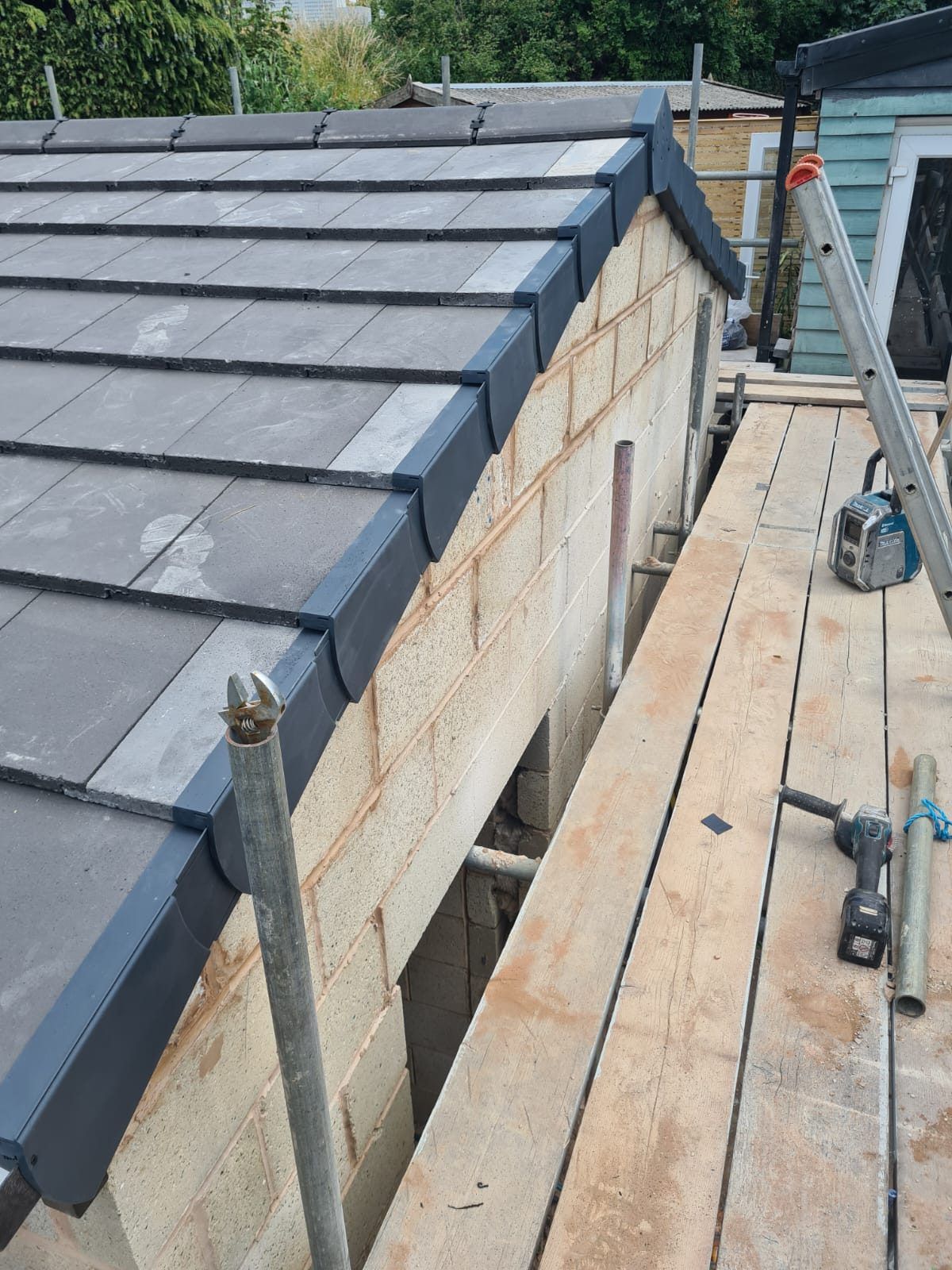 Grey tiled extension roof with a dry verge along the gable