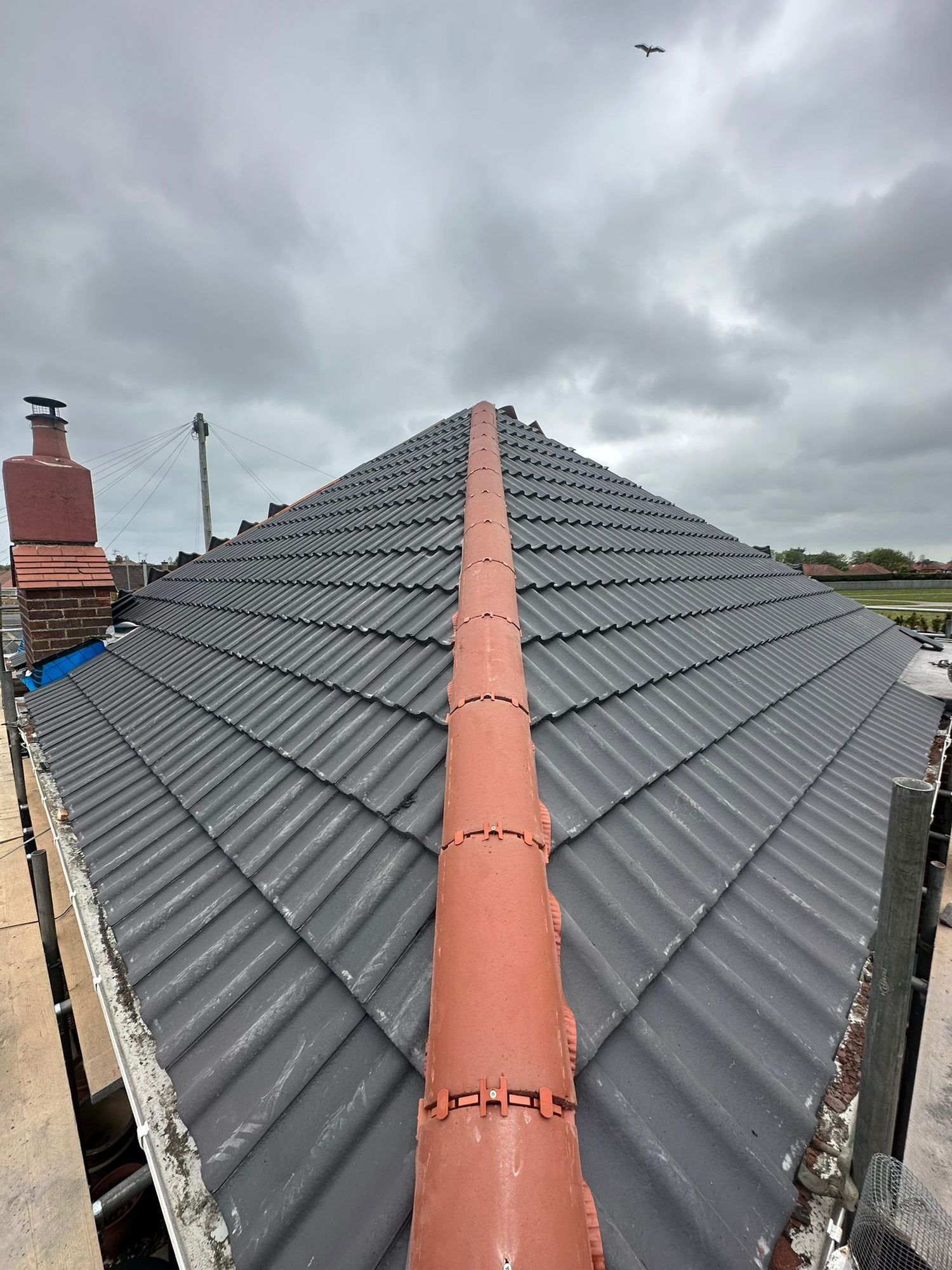 Grey tiled roof with new red ridge tiles