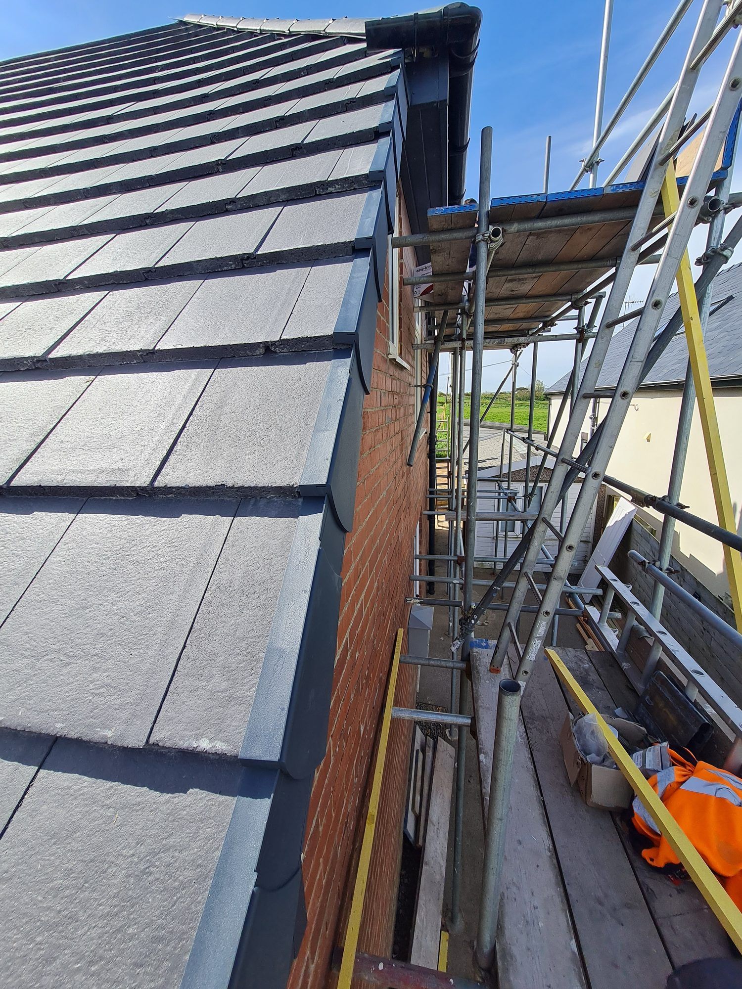 New grey tiled roof beside the scaffold
