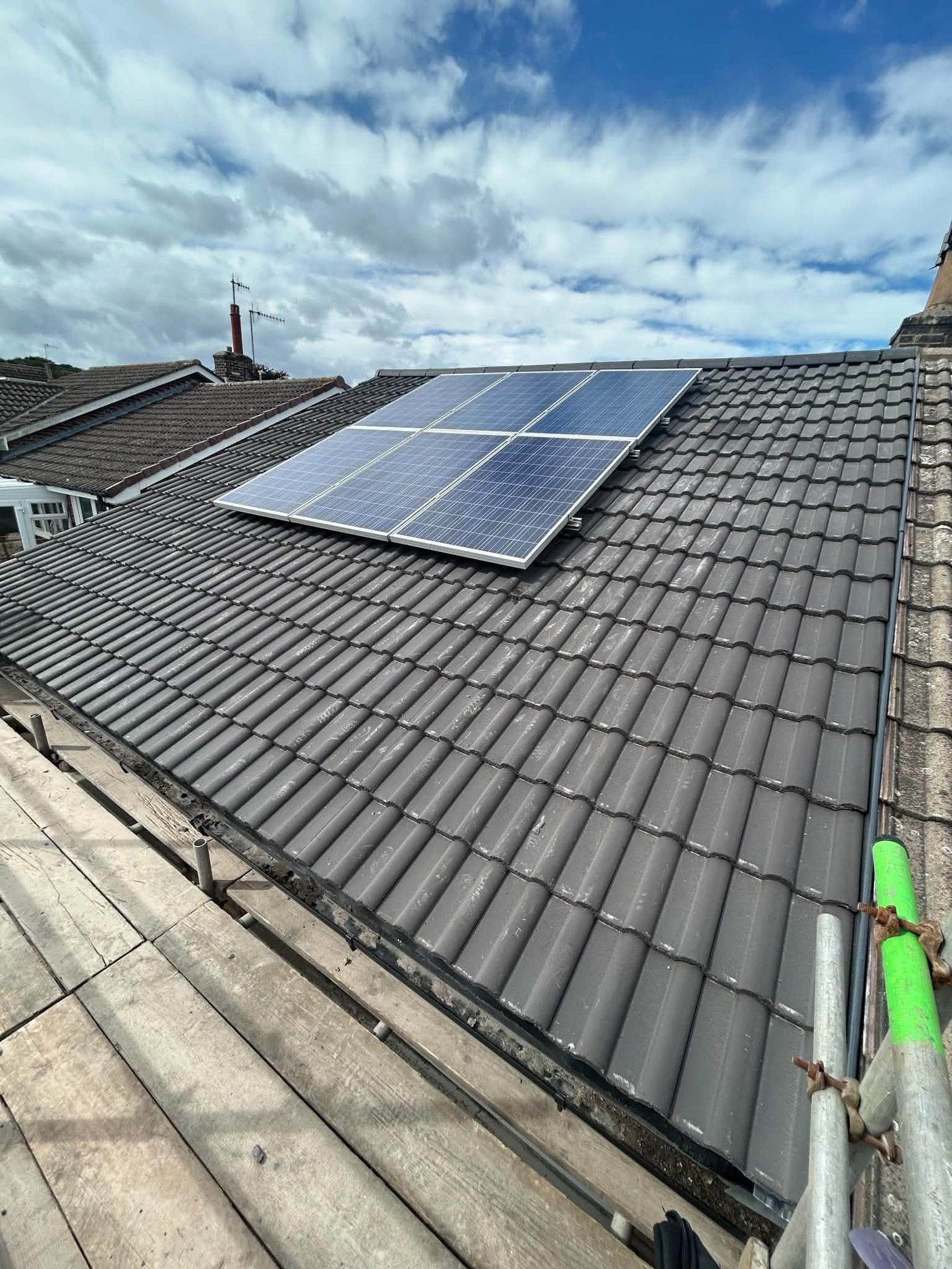 New grey tiled roof with solar panels, seen from the scaffold