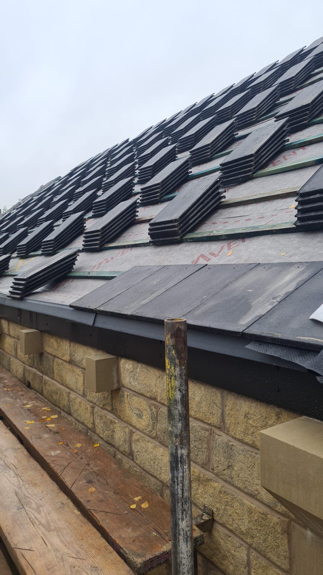 New grey tiles meeting a stone wall