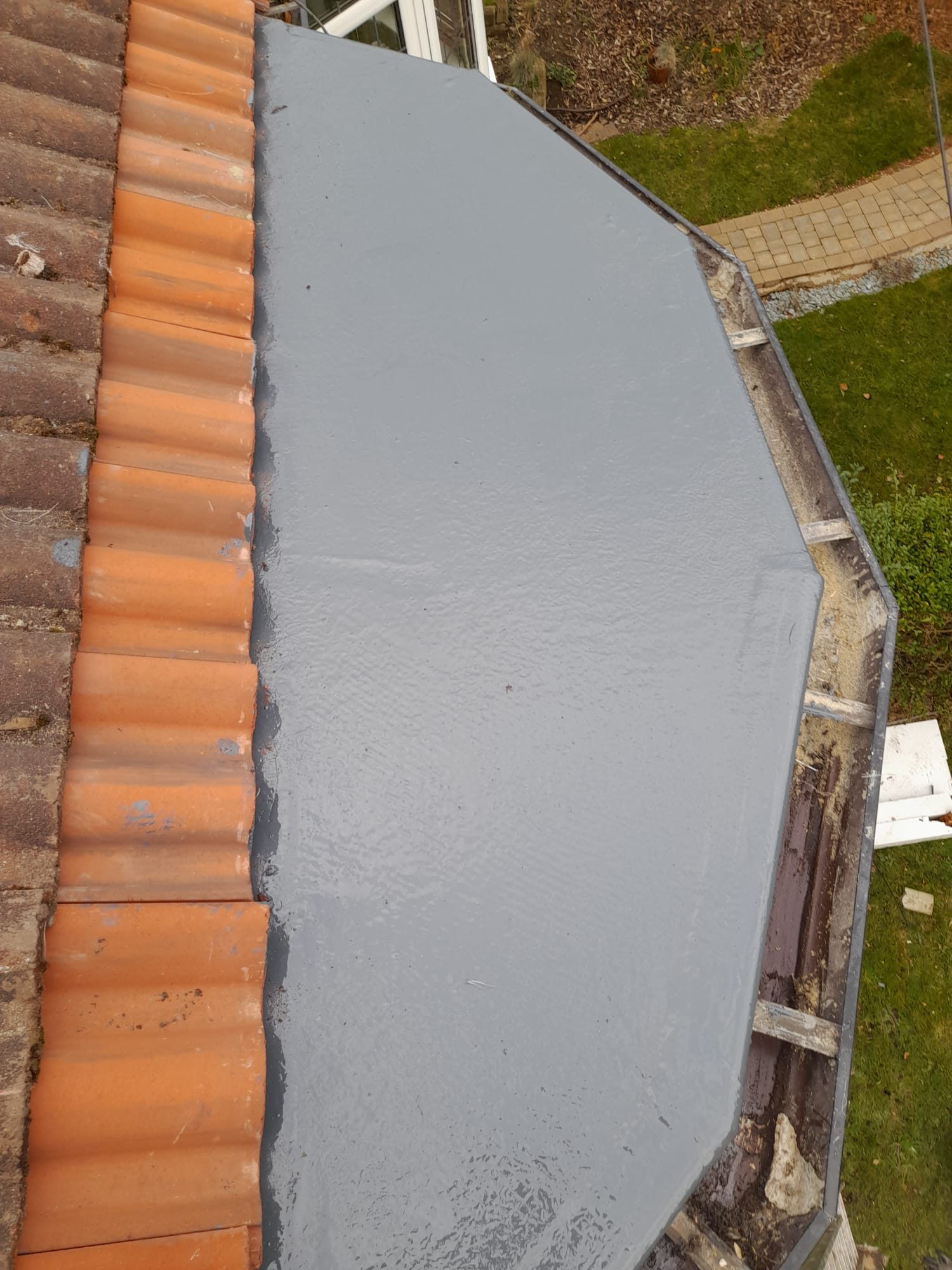 Grey GRP flat roof running alongside clay ridge tiles