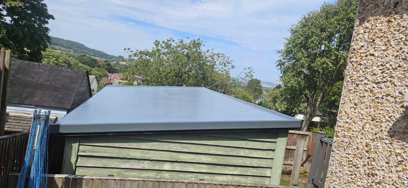 New grey GRP flat roof on a timber garden room, with hills beyond
