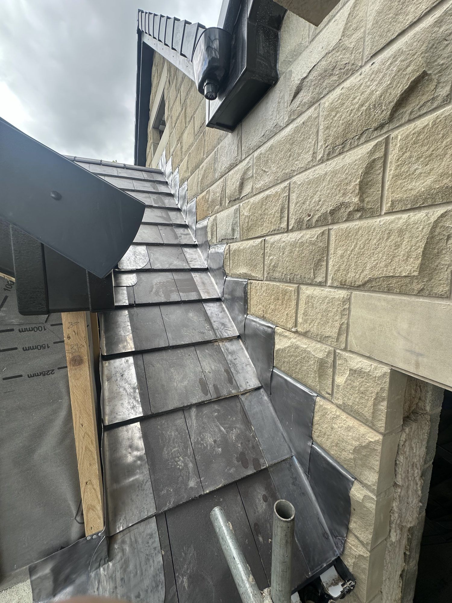 New slates and lead flashing where a roof meets a stone wall
