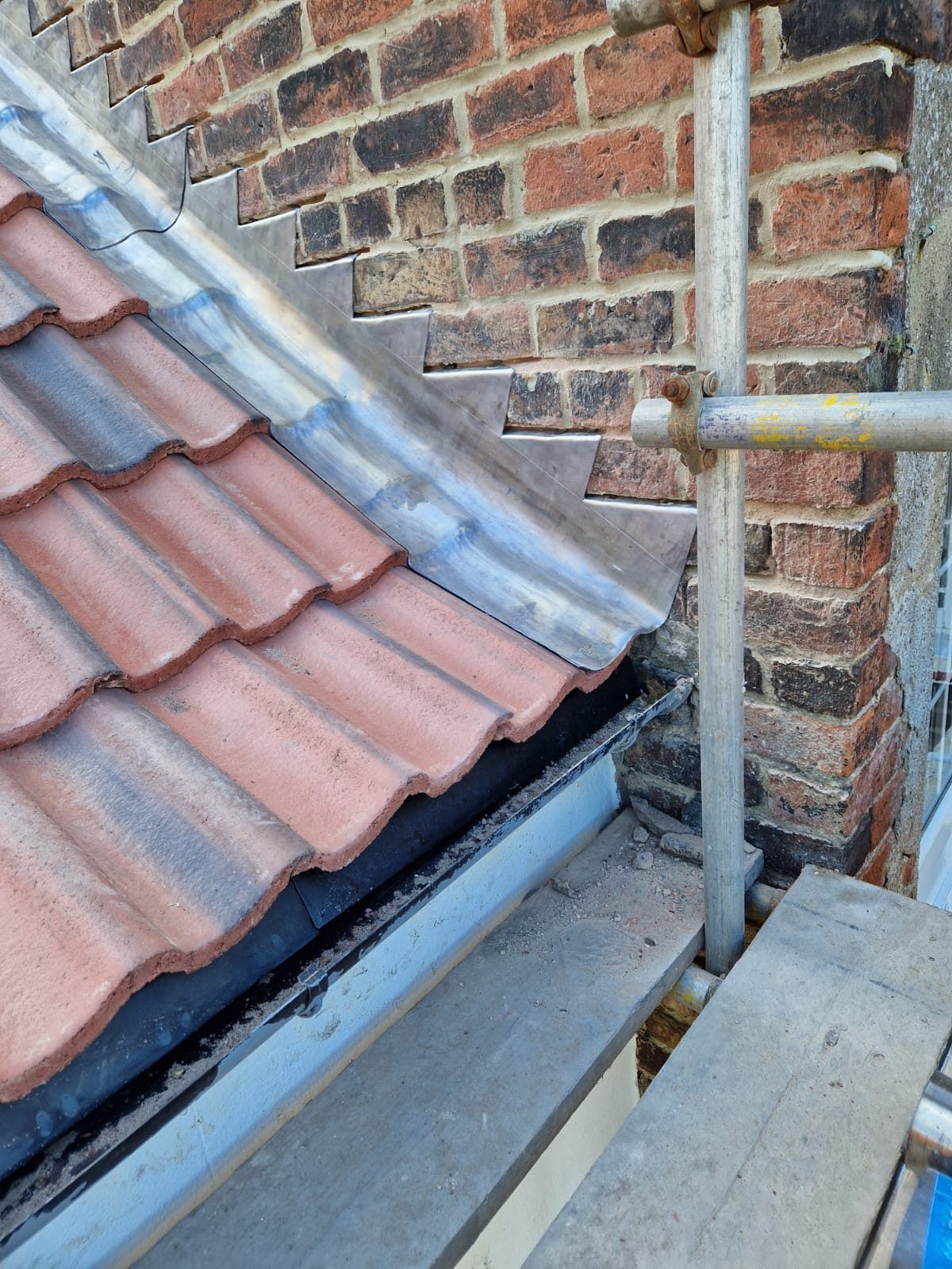 Red tiles and a lead-lined valley gutter beside a brick wall