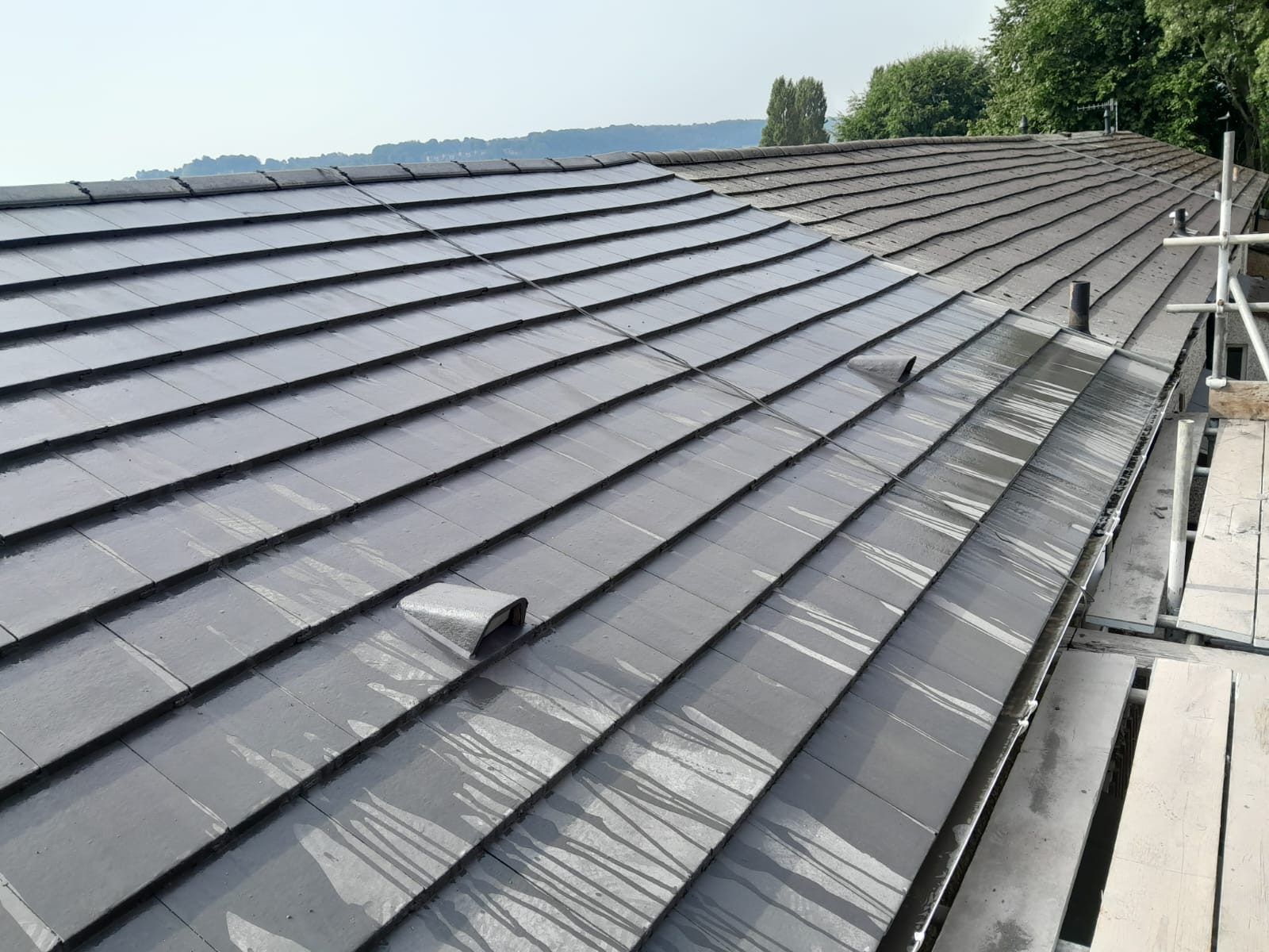 Long new grey tiled roof with a roof vent