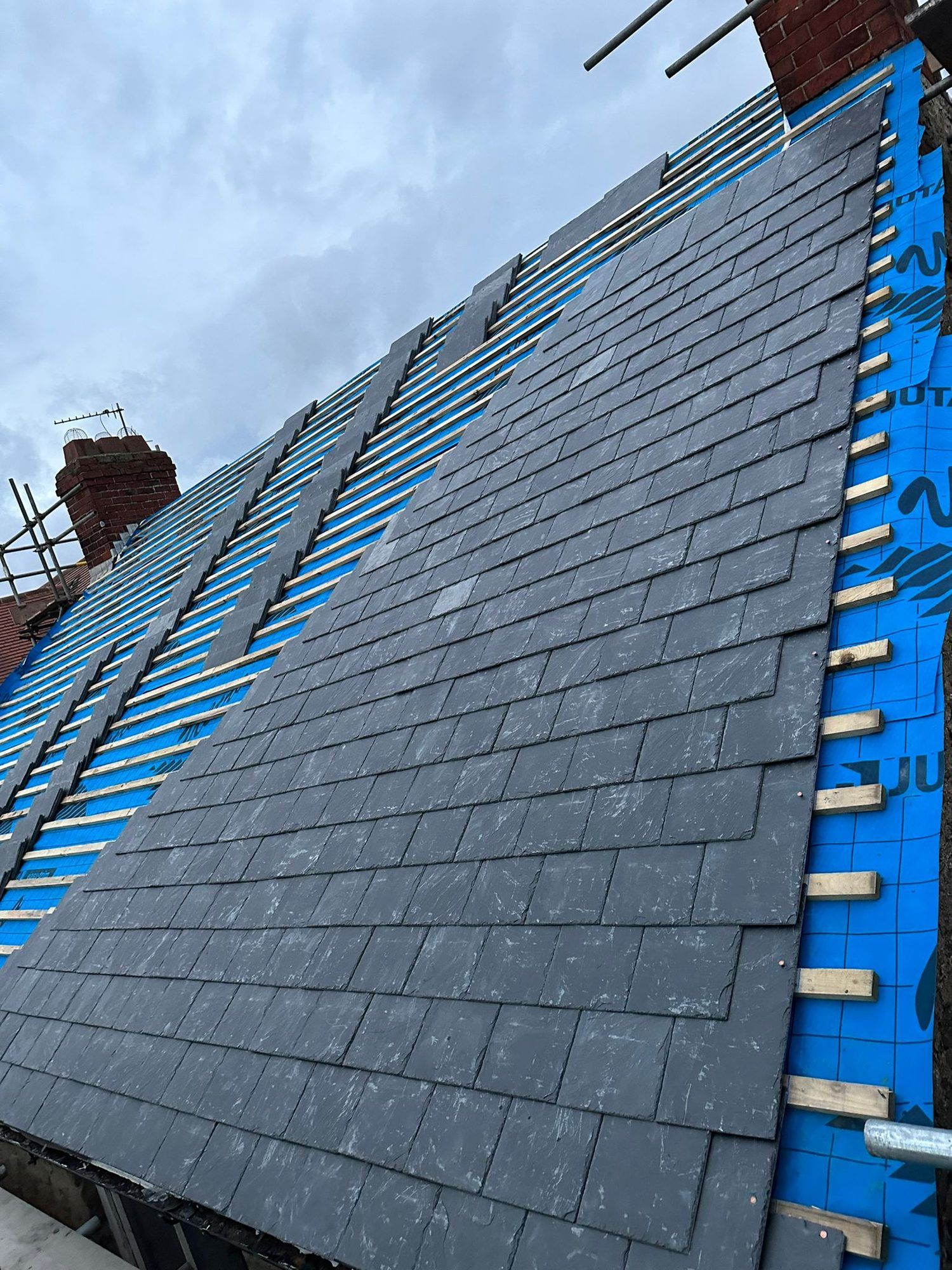New grey slates being laid over blue breathable membrane and battens