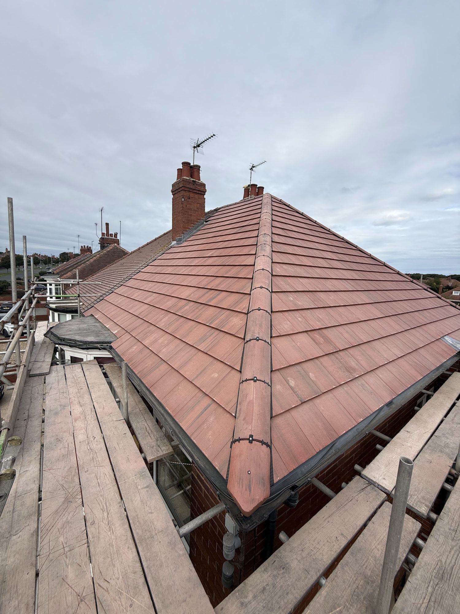 Red tiled hip roof with a new dry hip, seen from the scaffold