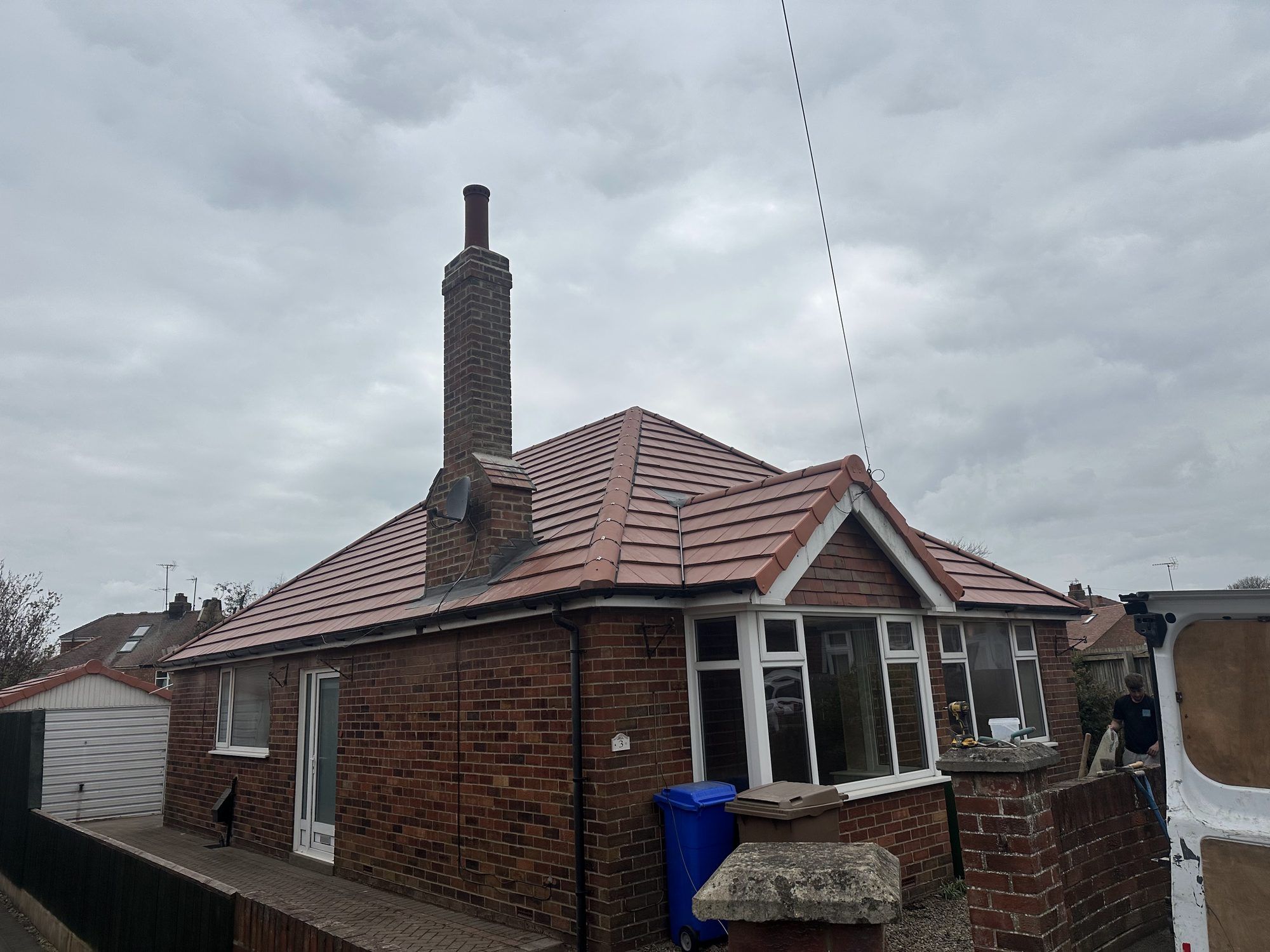 Bungalow with a red tiled roof and a tall brick chimney