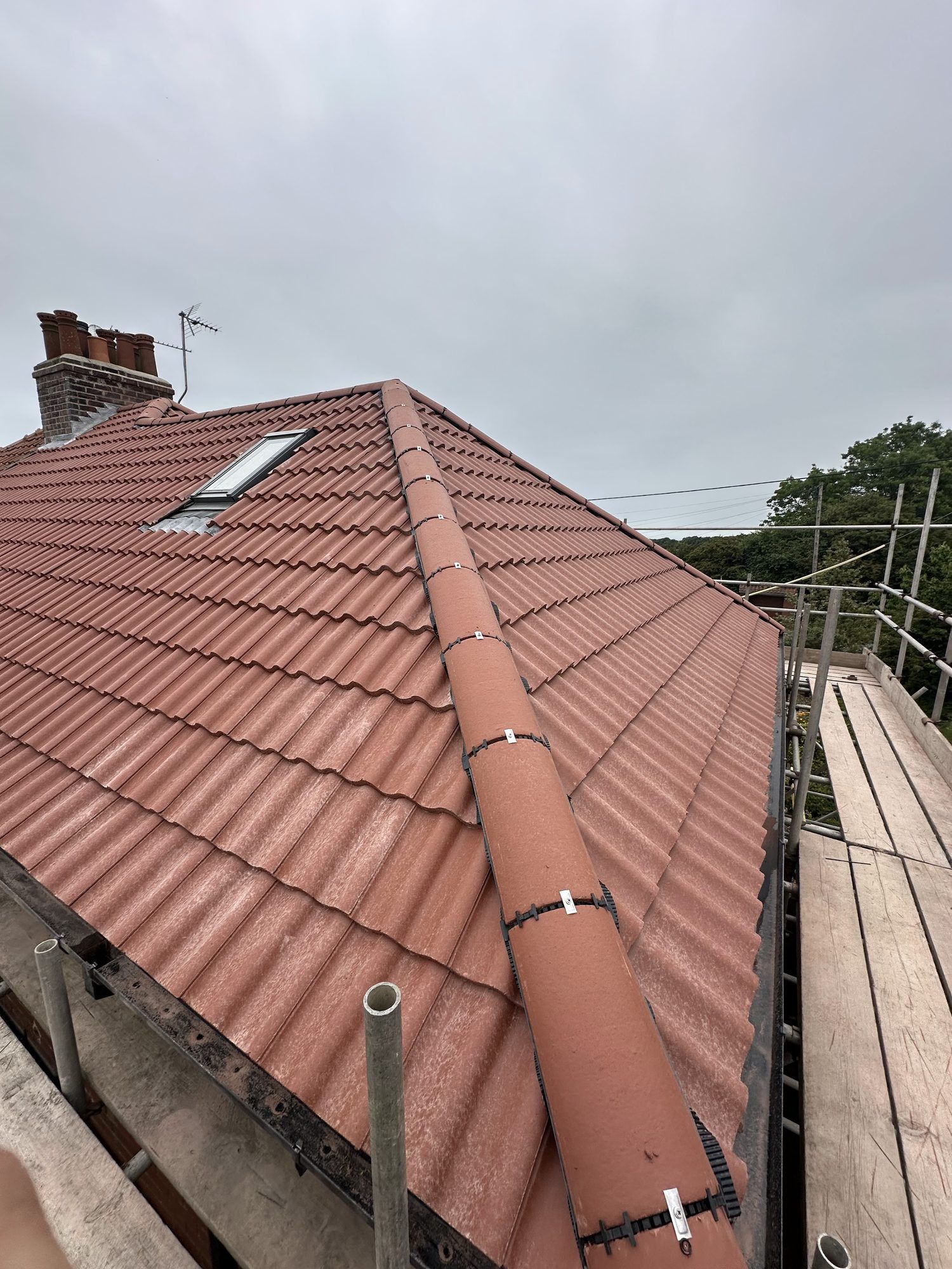 Red tiled roof with a roof window and a new dry ridge