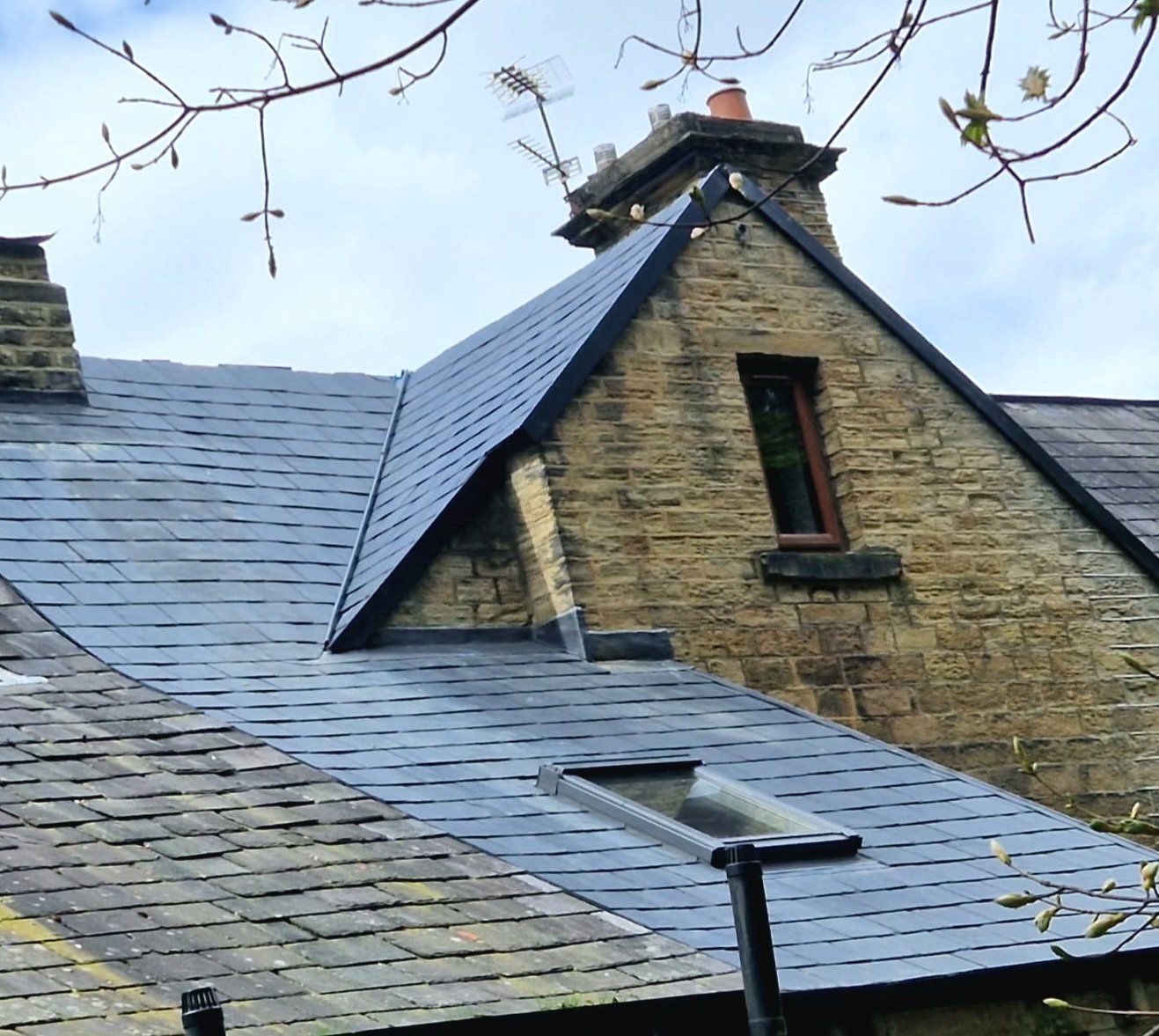 Slate roof around a stone gable dormer, with a roof window