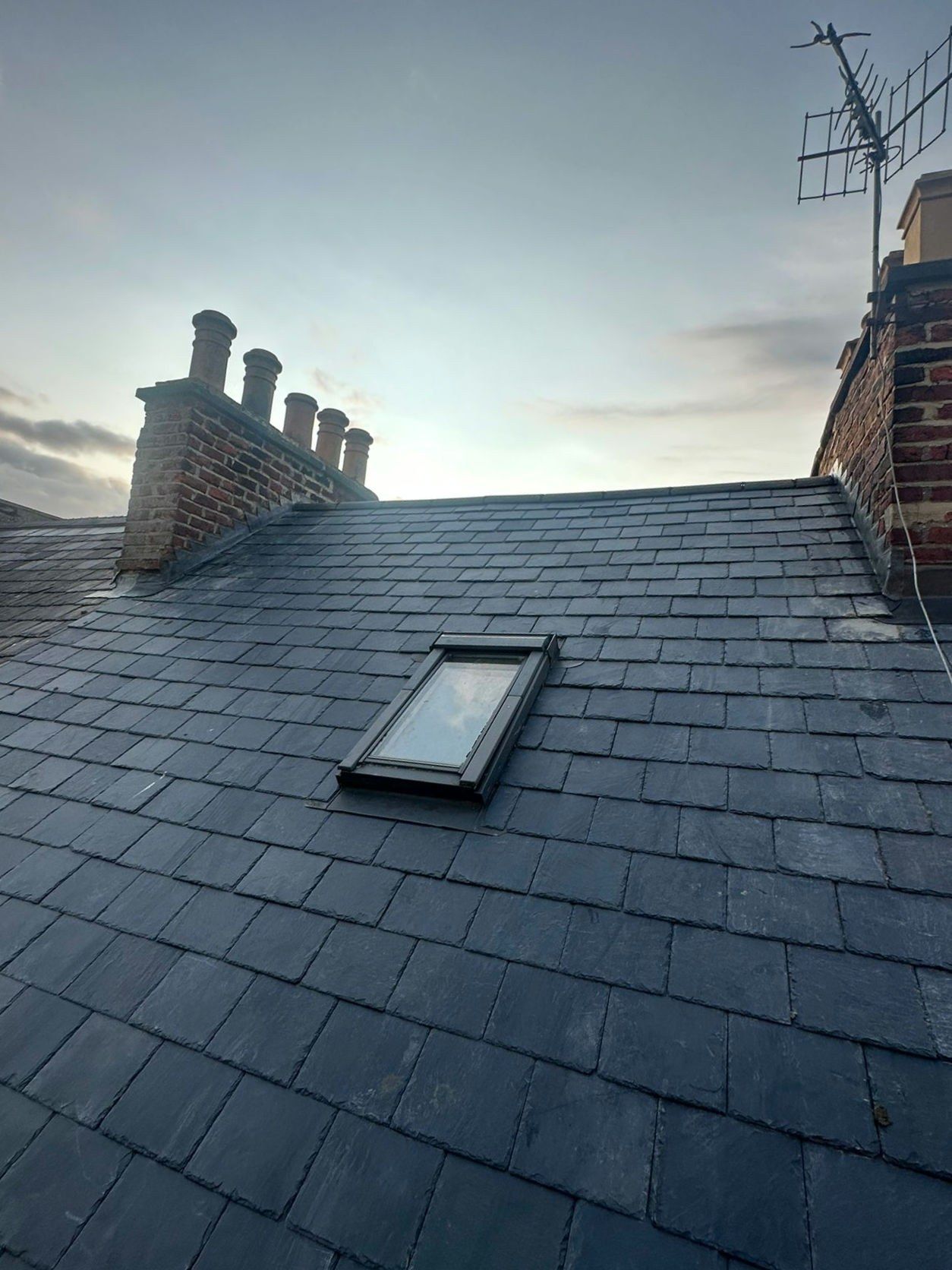 Slate roof with a roof window and chimney pots