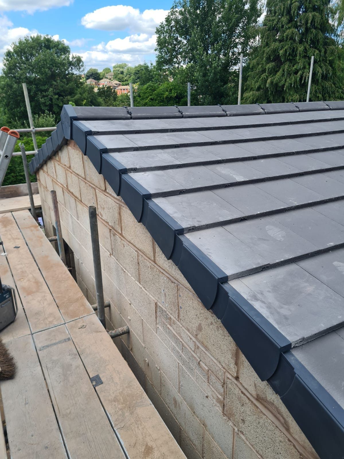 Grey tiles on a new stone extension, seen from the scaffold